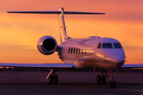 A business jet on the tarmac in front of a sunset