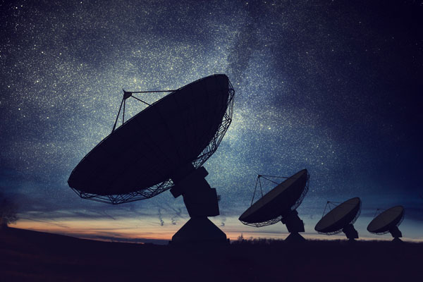 Ground stations for satellite communications in front of a starry sky