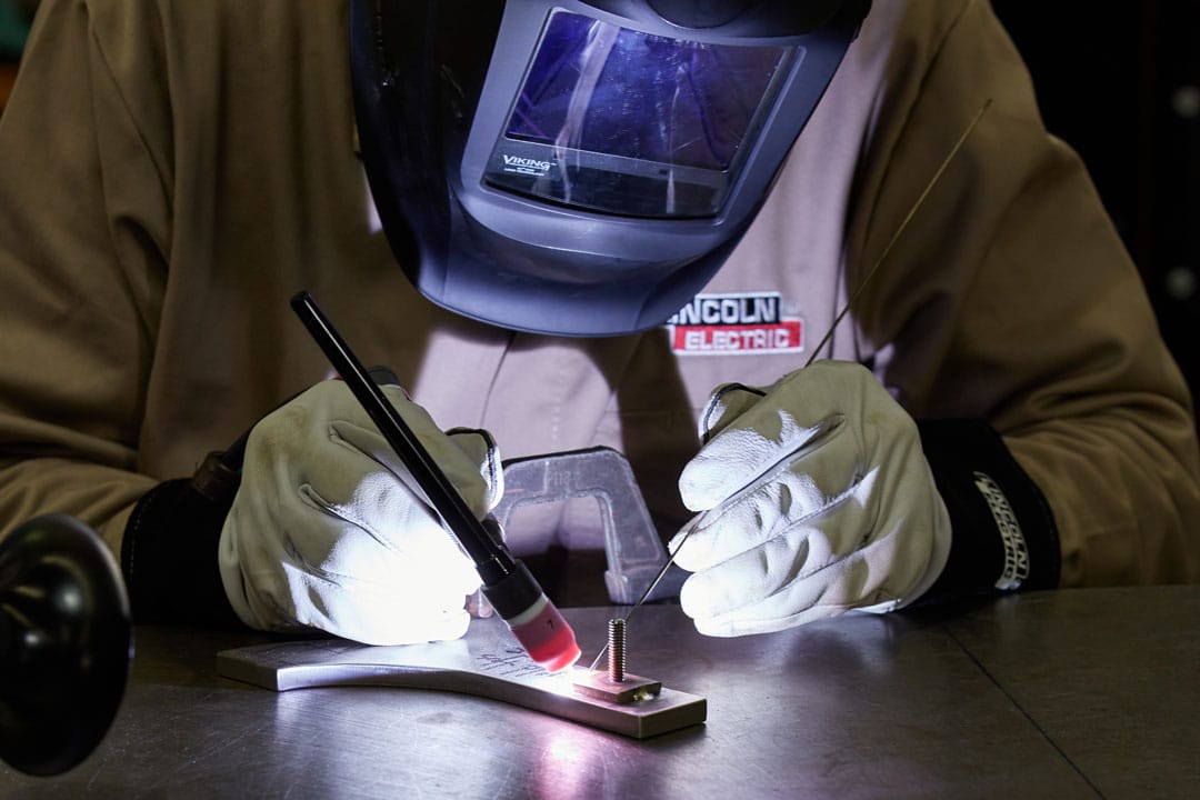 A fabricator TIG (GTAW) welding a custom metal component for an architectural application