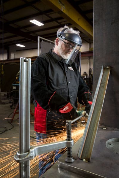 A fabricator grinding a large steel component for the automotive industry