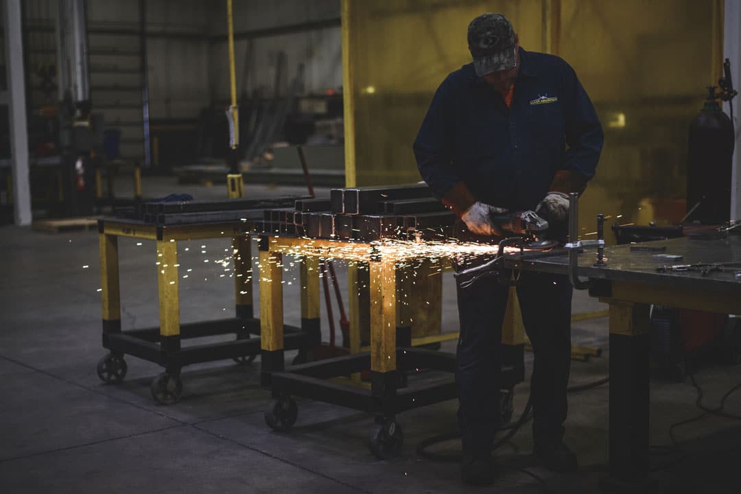 Fabricator grinding an automotive tooling component