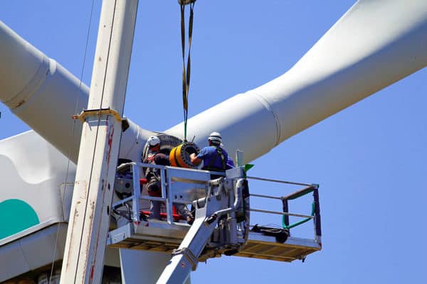 A technician on a lift repairing a windmill
