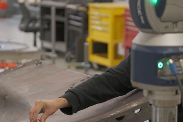 A quality technician inspecting a large metal tool with a laser tracker