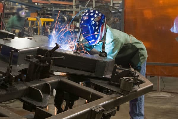A fabricator welding a large steel weldment for heavy equipment manufacturing