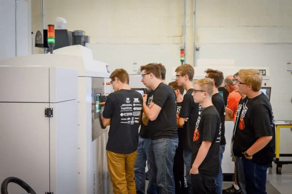 Students looking into a DMLS 3D printer at Baker Industries