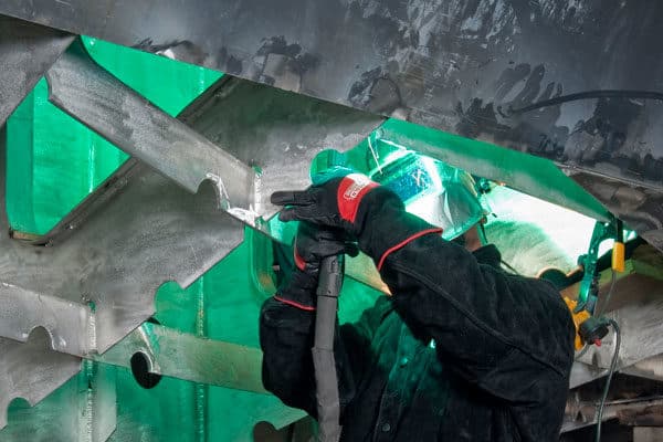 A fabricator welding a large metal part for the shipbuilding industry