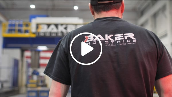 A worker walking toward the Emco MECOF Powermill, one of the largest 5-axis CNC machines in the world, with a play button overlaying the image